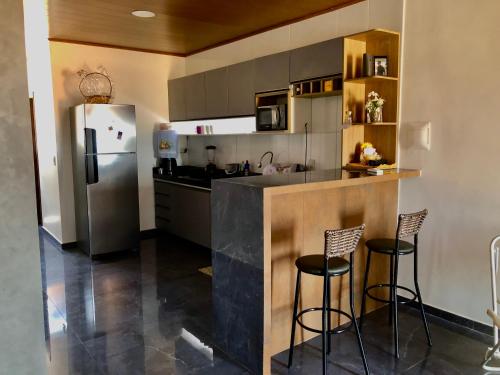 una cucina con un bar con due sgabelli e un frigorifero di Aconchego a Maceió