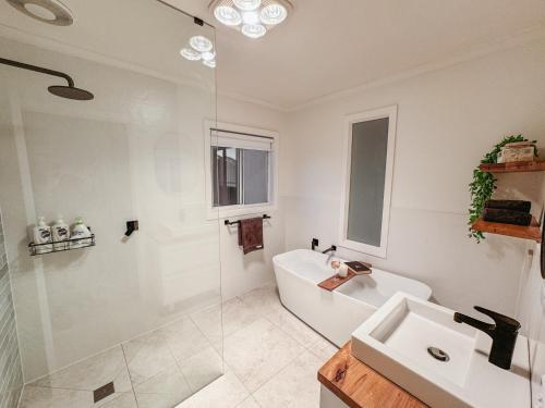a bathroom with a tub and a sink and a shower at The Big Isle Retreat in Cowes