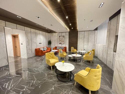 a lobby with yellow chairs and tables and a couch at كويت سفن للشقق المخدومة in Jeddah