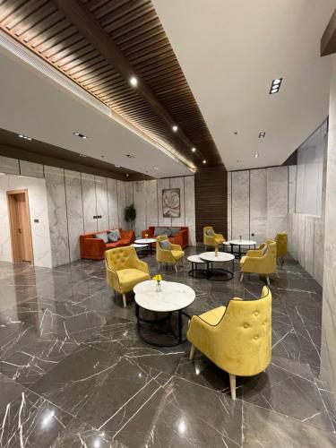 a lobby with yellow chairs and tables and chairs at كويت سفن للشقق المخدومة in Jeddah