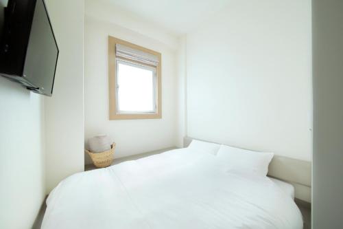 a bedroom with a white bed and a window at Hotel Nupka in Obihiro