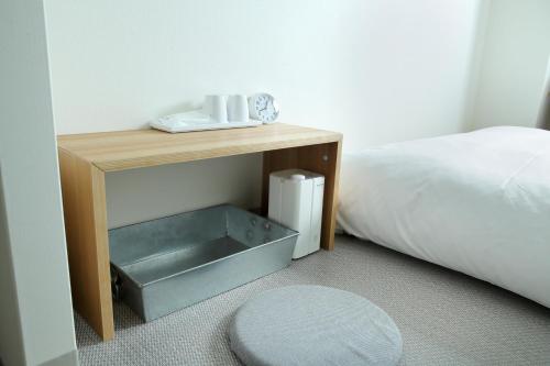 a wooden table with a drawer next to a bed at Hotel Nupka in Obihiro