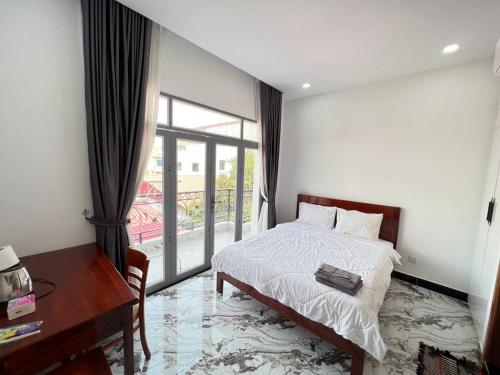 a bedroom with a bed and a desk and a window at Jasminsorium in Phnom Penh