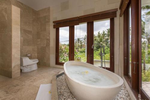 a large bathroom with a tub and a toilet at Dragonville 3BR Private Pool Canggu Residence CYN in Mantaak
