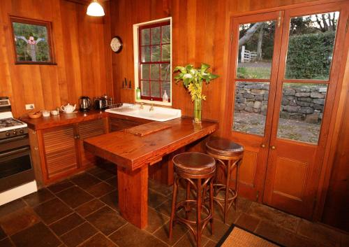 a kitchen with a wooden table and stools in it at Hermitage Cottage in Kurrajong