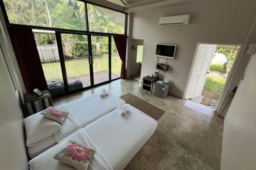 a bedroom with a white bed and a large window at Kalacanal resort in Ban Bang Khan Taek (1)