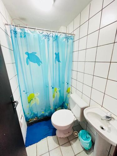 a bathroom with a toilet and a shower curtain with fish at Village prainha in Arraial do Cabo