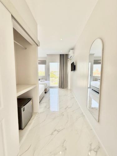 a white room with two beds and a mirror at โรงแรมแรบบิท Rabbit Hotel Nangrong in Nang Rong