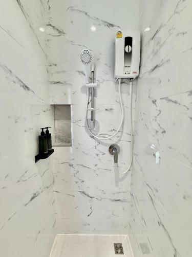a bathroom with a shower with white marble walls at โรงแรมแรบบิท Rabbit Hotel Nangrong in Nang Rong