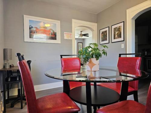 a dining room with a glass table and red chairs at Dundee Escape in Charleston