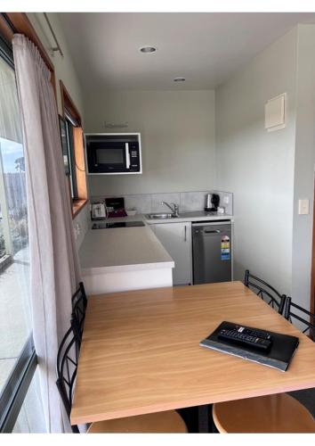 a small kitchen with a wooden table and a counter top at Haast Beach Motel in Haast