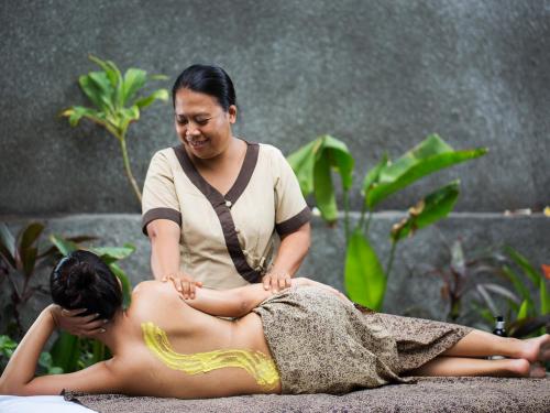 a woman sitting on the ground performing a massage at The Leaf Jimbaran in Jimbaran