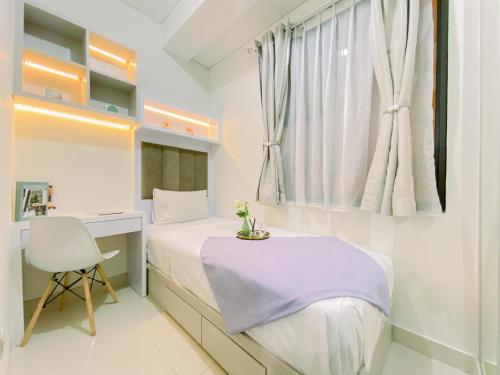 a white bedroom with a bed and a desk and a window at Good Place and Homey 2BR at Transpark Cibubur Apartment near Mall By Travelio in Depok