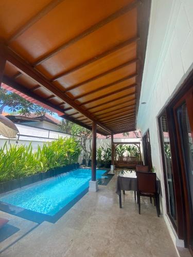 a swimming pool in the middle of a patio with a wooden ceiling at Classic Villa with Private Pool in Kuta