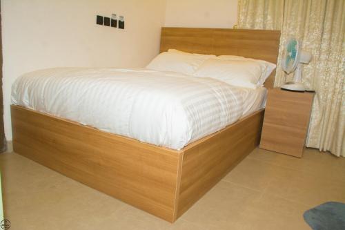 a bed with a wooden bed frame in a room at 1BD Serenity Dubai Suite in Abuja