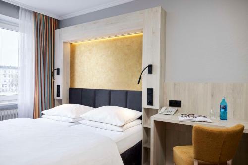 a hotel room with a bed and a desk with a phone at Best Western Raphael Hotel Altona in Hamburg