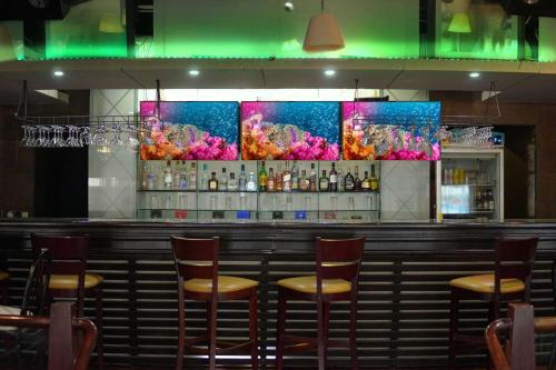 a bar with wooden stools in a restaurant at Wyndham Garden Los Mochis Plaza Inn in Los Mochis
