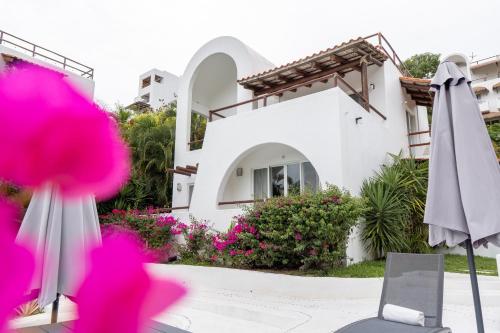 a white house with pink flowers and an umbrella at Condos Privados en Huatulco in Tangolunda
