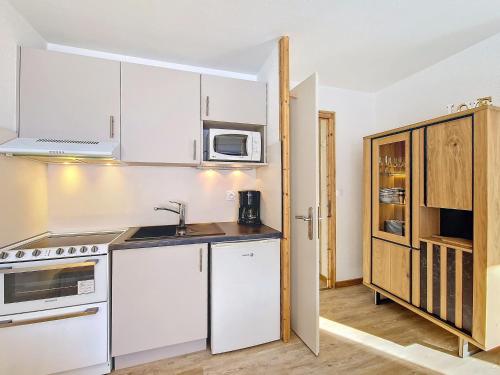 une cuisine avec des armoires blanches et un micro-ondes dans l'établissement Appartement cosy à La Clusaz, 6 pers, WiFi, parking, animaux admis - FR-1-818-19, à La Clusaz