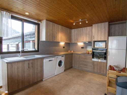 une cuisine avec des armoires en bois et une laveuse et une sécheuse dans l'établissement La Clusaz : Apt 10 pers, terrasse, wifi, animaux ok - FR-1-818-48, à La Clusaz