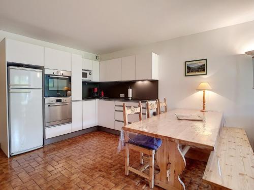 une cuisine avec une table en bois et des armoires blanches dans l'établissement Appartement cosy à La Clusaz - 6 pers, animaux admis, parking - FR-1-818-76, à La Clusaz