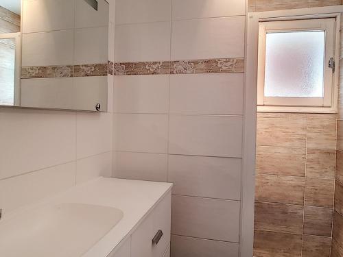 une salle de bain blanche avec un lavabo et une fenêtre dans l'établissement La Clusaz : Appartement 7 pers avec balcons, animaux admis, parking - FR-1-818-2, à La Clusaz