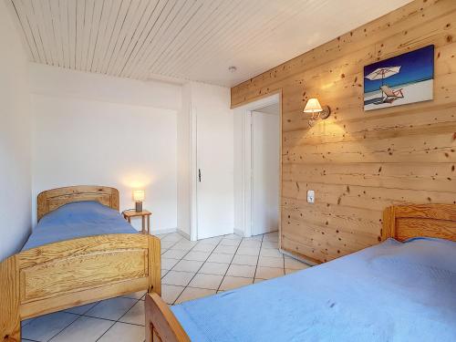 deux lits dans une chambre aux murs en bois dans l'établissement La Clusaz : Appartement pour 4 pers, Animaux admis, Balcon et Parking - FR-1-818-91, à La Clusaz