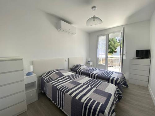 deux lits dans une chambre blanche avec une fenêtre dans l'établissement Saint-Palais : T2 3 étoiles, proche plage, terrasse sud, parking, clim et Wifi - FR-1-738-36, à Saint-Palais-sur-Mer