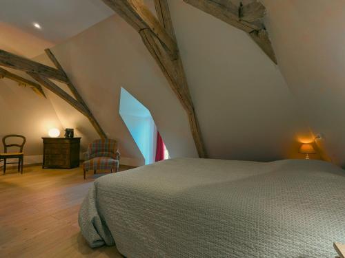 an attic bedroom with a bed and a chair at Gîte charmant avec parking, animaux acceptés, près du Château de Clavières - FR-1-591-718 in Ardentes