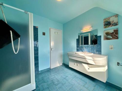 La salle de bains bleue est pourvue d'un lavabo et d'une douche. dans l'établissement Maison calme à Carnac, 3 pièces, jardin, parking, proche plages - FR-1-377-97, à Carnac