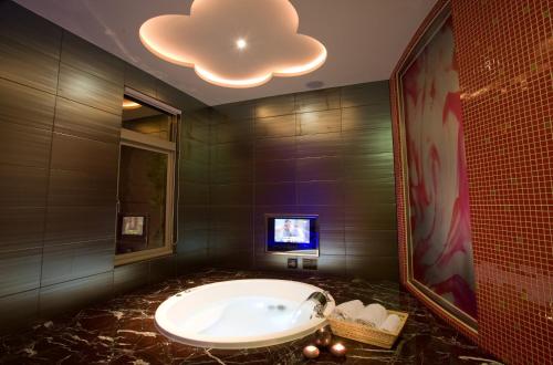 a bathroom with a tub and a tv on the wall at Yes Motel in Zhonghe