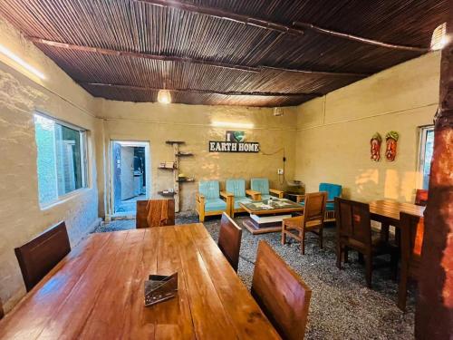 Katarniān GhātEarth Home Katarniaghat的配有木桌椅的餐厅