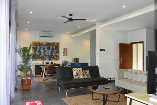 a living room with a couch and a ceiling fan at 2 Bedroom Villa with Pool & Close to Setangi Beach in Mangsit