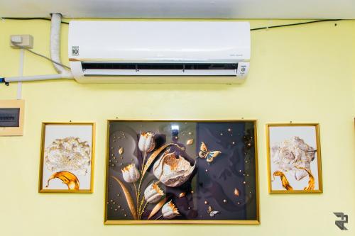a wall with three pictures of flowers and a air conditioner at Affordable Up To 15 Pax Near Aqua Planet & Dinosaur Island in Angeles