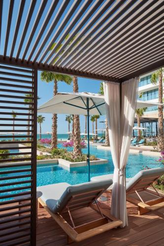 a pool with two lounge chairs and an umbrella at Mandarin Oriental Jumeira, Dubai in Dubai