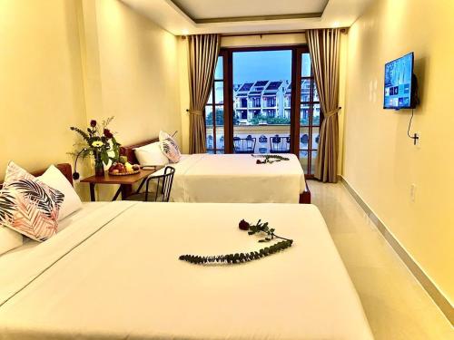a hotel room with two beds with a necklace on the bed at Aman Riverside Hotel in Hoi An