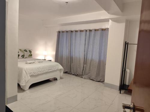 a white bedroom with a bed and a window at RedDoorz at Pilgrims Hotel in Bulatok