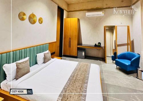 a bedroom with a large bed and a blue chair at Kavyum Retreat in Himatnagar