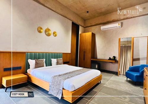 a bedroom with a large bed and a blue chair at Kavyum Retreat in Himatnagar