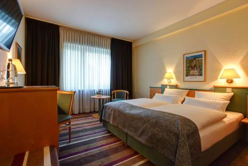 a hotel room with a large bed and a table at Sure Hotel by Best Western Ambassador Duesseldorf in Düsseldorf