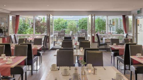 a restaurant with tables and chairs and windows at Best Western Hotel Darmstadt Mitte in Darmstadt