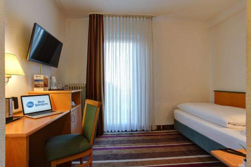 a hotel room with a bed and a desk with a laptop at Sure Hotel by Best Western Ambassador Duesseldorf in Düsseldorf