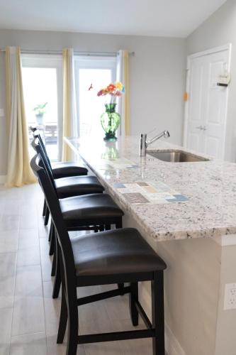 a kitchen with a counter with a row of bar stools at Sea Lion Serenity Retreat - New Construction 2024 in Port Saint Lucie