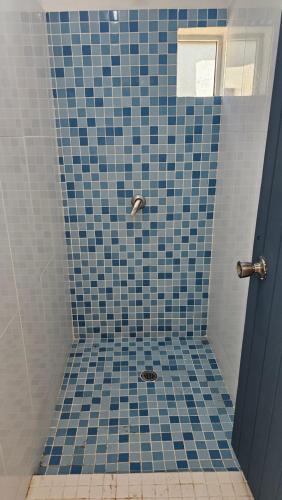 a bathroom with a blue tiled shower with a drain at Octopus Resort in Nalauwaki