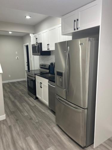 a kitchen with a stainless steel refrigerator and white cabinets at Entire 2 Ensuite Bedrooms in a Basement in Edmonton