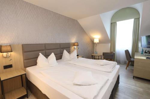 a hotel room with a large bed with white pillows at Best Western Hotel Rosenau in Bad Nauheim
