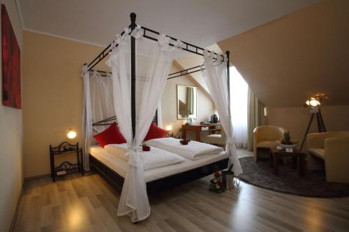 a bedroom with a canopy bed with red pillows at Best Western Hotel Rosenau in Bad Nauheim