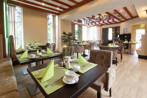 a dining room with tables and chairs with green napkins at Best Western Hotel Rosenau in Bad Nauheim
