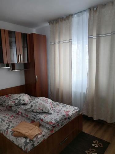 a bedroom with a bed and a window with curtains at Cabana Daria in Gîrda de Sus