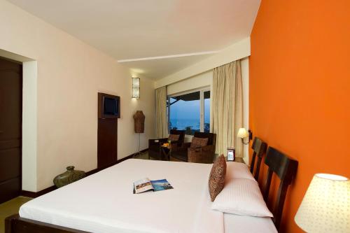 a bedroom with a bed with an orange wall at Sparsa Resort Kanyakumari in Kanyakumari